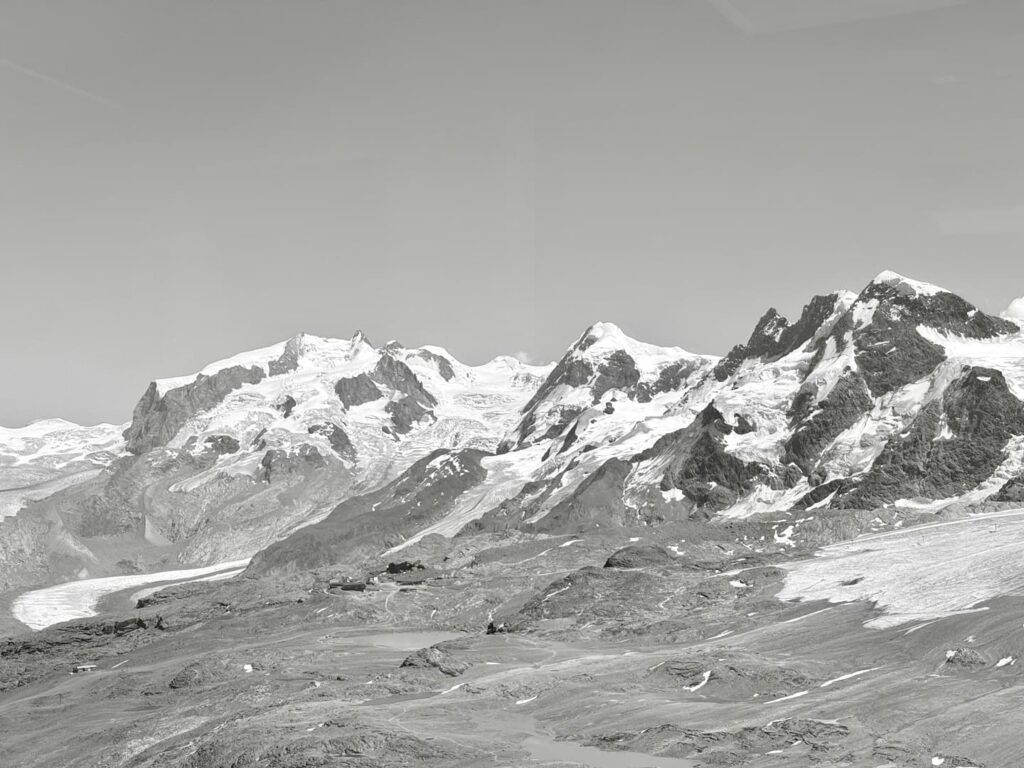Schneebedeckte Berge unter klarem Himmel, mit felsigen Hängen und Eis- oder Schneeflecken am Boden, bilden eine beeindruckende Alpenlandschaft – perfekte Bedingungen für ein unvergessliches Erlebnis auf der Dom- und Dufourspitze.